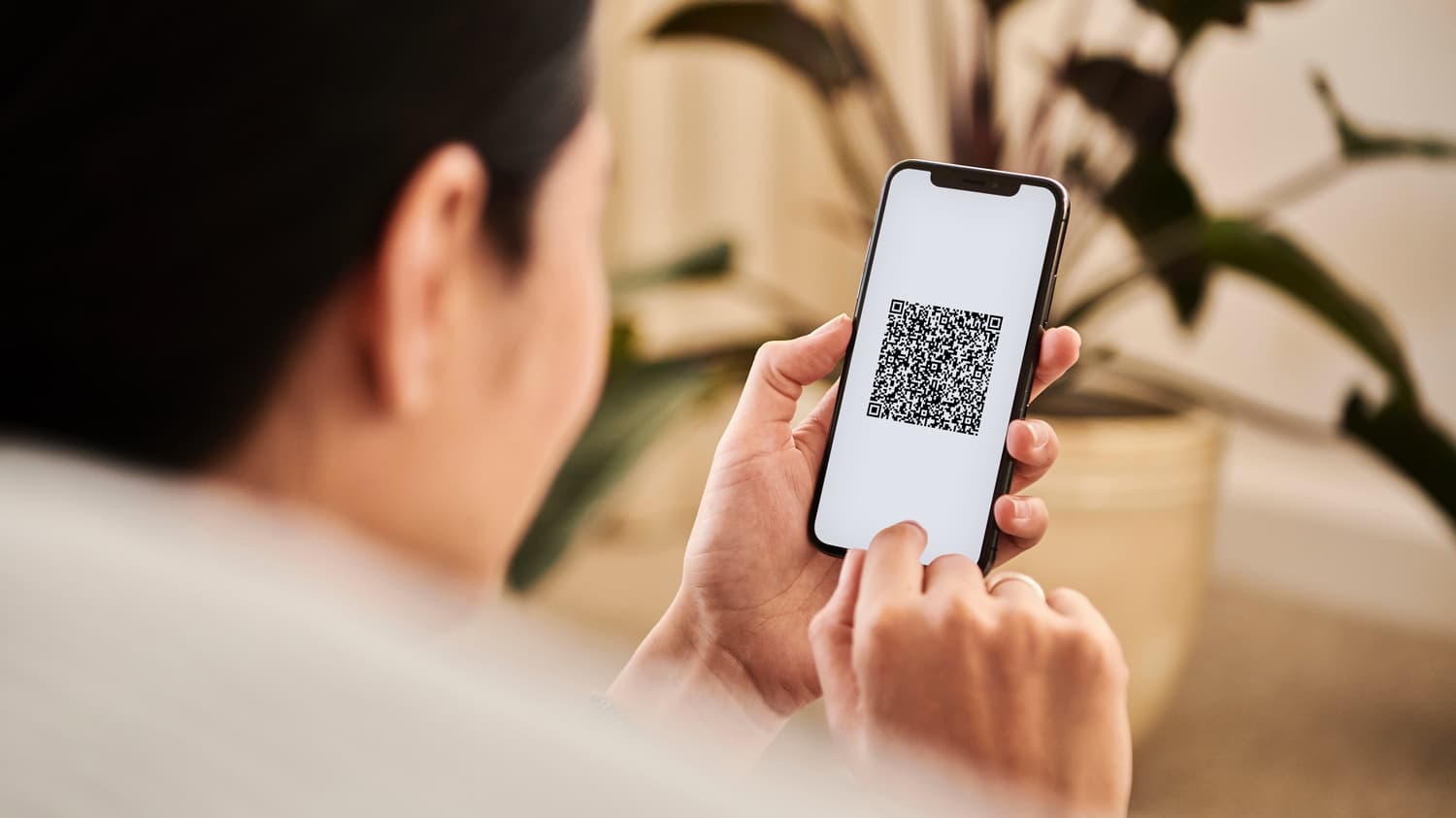 Frau hält ein Smartphone, das einen QR-Code zum Scannen anzeigt
