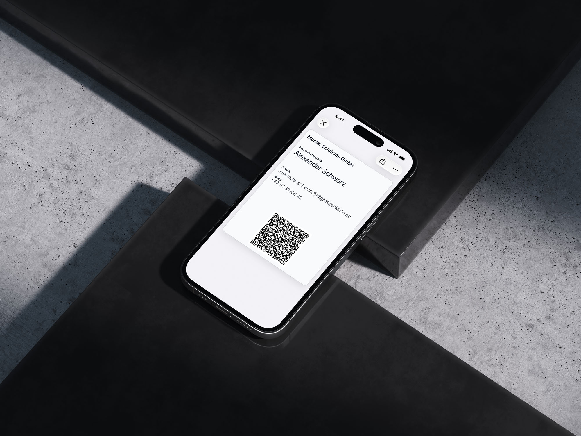 Ein iPhone liegt angewinkelt auf dunklen Betonstufen und zeigt eine cremeweiße digitale Visitenkarte im Apple Wallet: Muster Solutions GmbH, Projektmanager Alexander Schwarz, mit E-Mail, Mobilnummer und QR-Code
